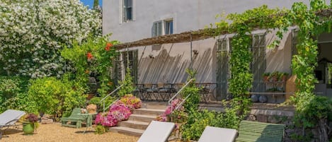 Un patio con mobiliario exterior, una pérgola y diversas plantas.