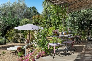 An outdoor patio with a table, chairs, and an umbrella. - Bed and Breakfast 'Chambre 4' with Shared Pool, Wi-Fi and Air Conditioning (La Motte)