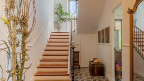 Eine Treppe mit einem geometrischen Muster im Boden, einer Topfpflanze und einer Vintage-Lampe.