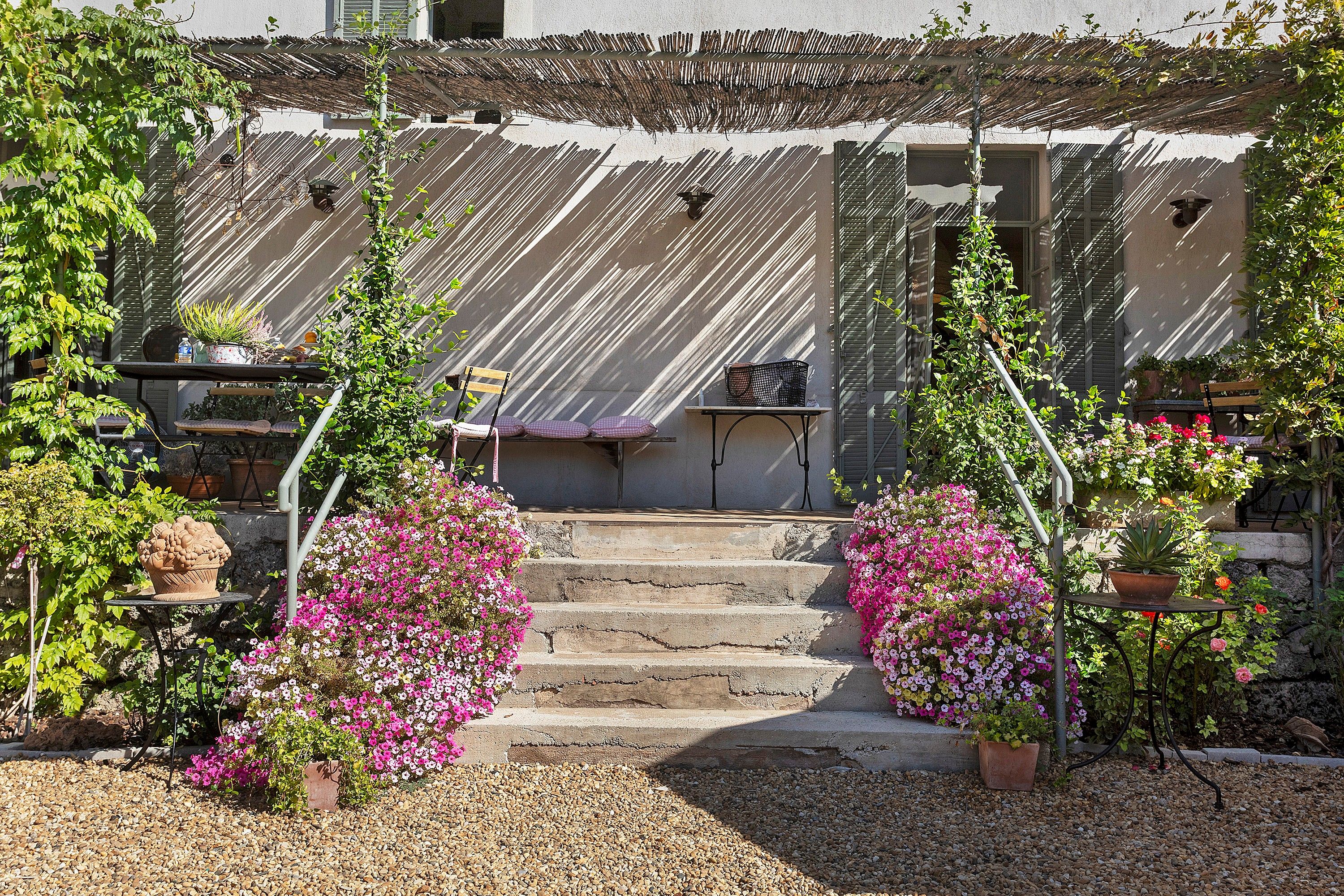 A building with a staircase leading to a door, surrounded by potted plants and flowers.