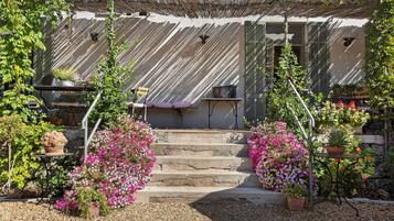 A building with a staircase leading to a door, surrounded by potted plants and flowers.