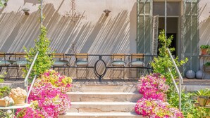 Außenstufen führen zu einem Gebäude mit einem Balkon, umgeben von Blumentöpfen und Blumen.