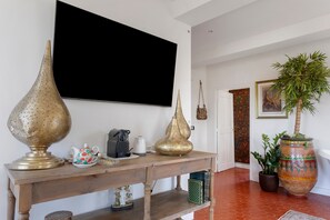 A living room with a wooden console table, a television mounted on the wall, and a potted plant.