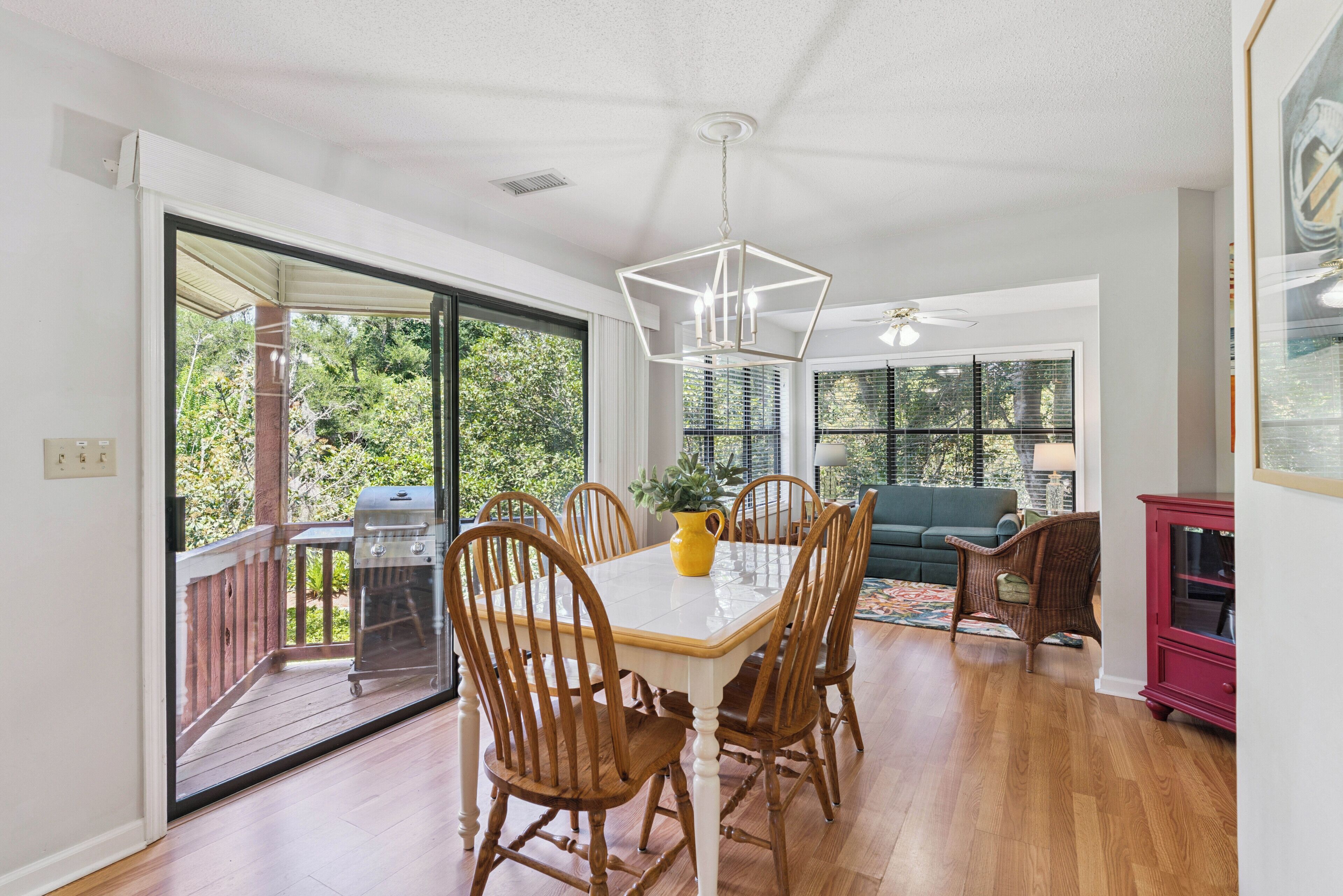 A dining area with a table, chairs, and a grill outside.