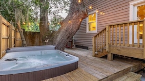 The private hot tub area features a welcoming deck surrounded by mature trees, with soft outdoor lighting creating a cozy evening ambiance perfect for your relaxation. - Twin Oaks in the Village area, sleeps 10 (St Simons Island)
