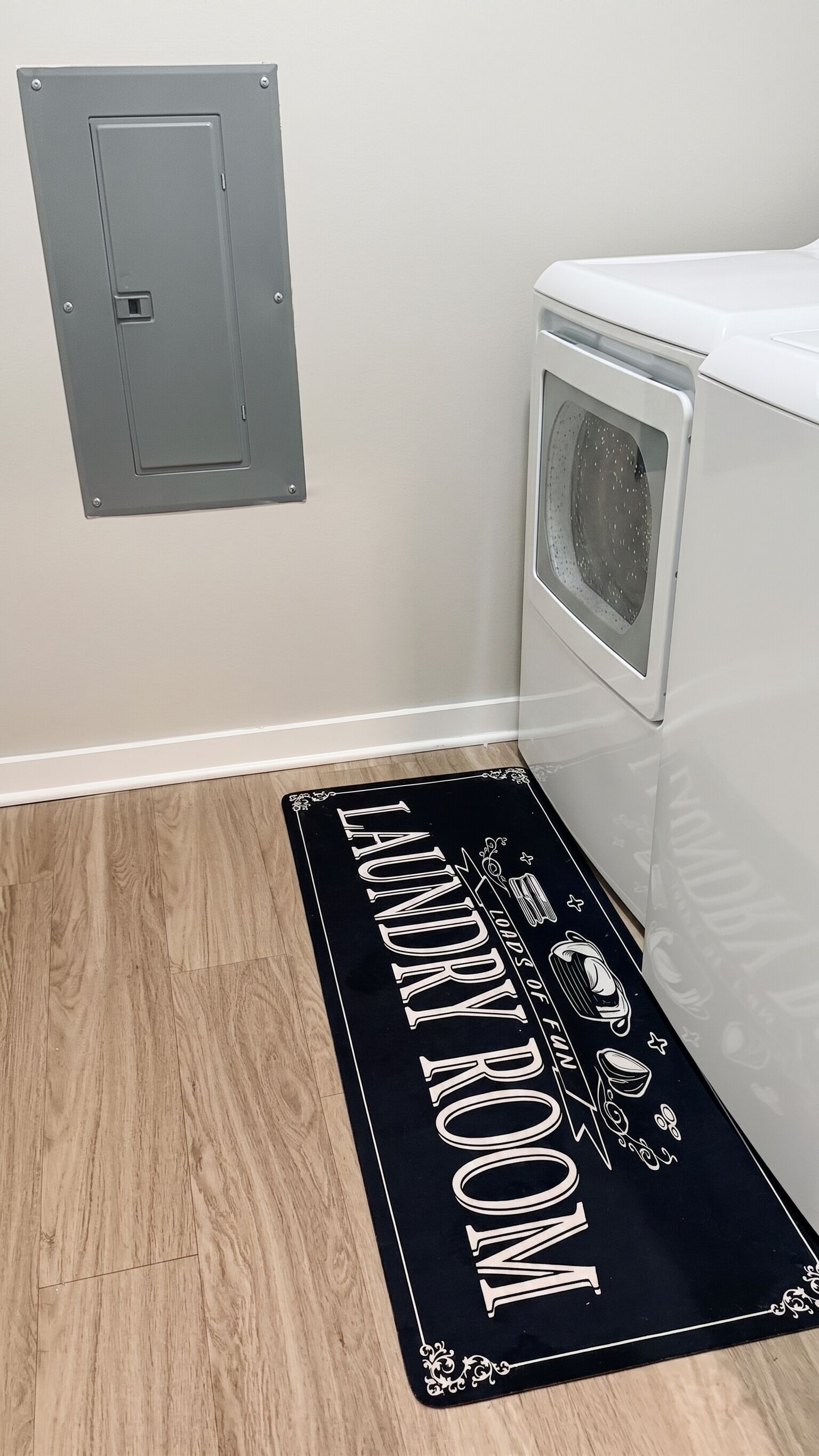 A laundry room with a door, a washing machine, and a black doormat with 'LAUNDRY ROOM' text.