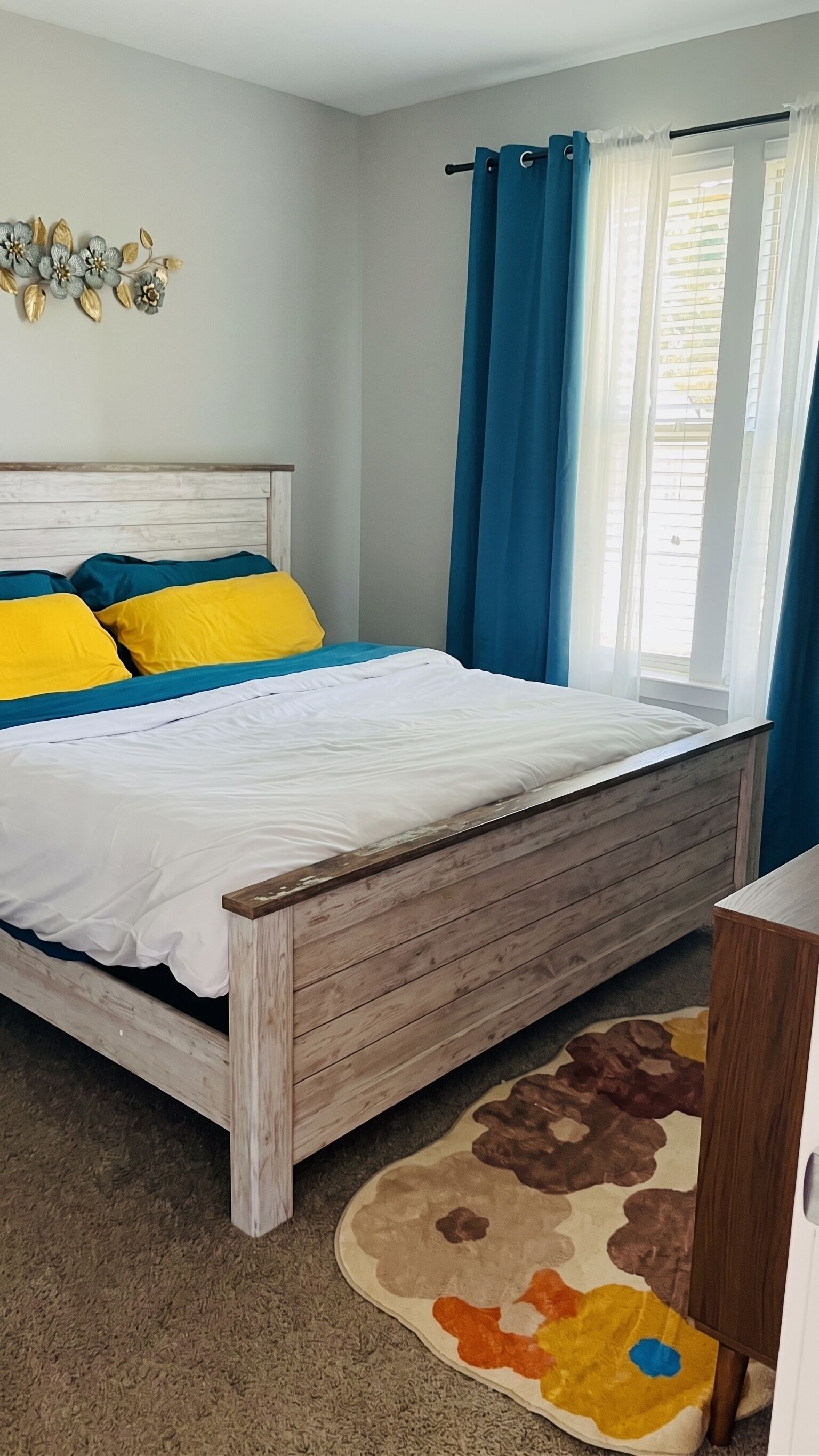 A bedroom with a wooden bed, blue curtains, and a decorative wall piece.