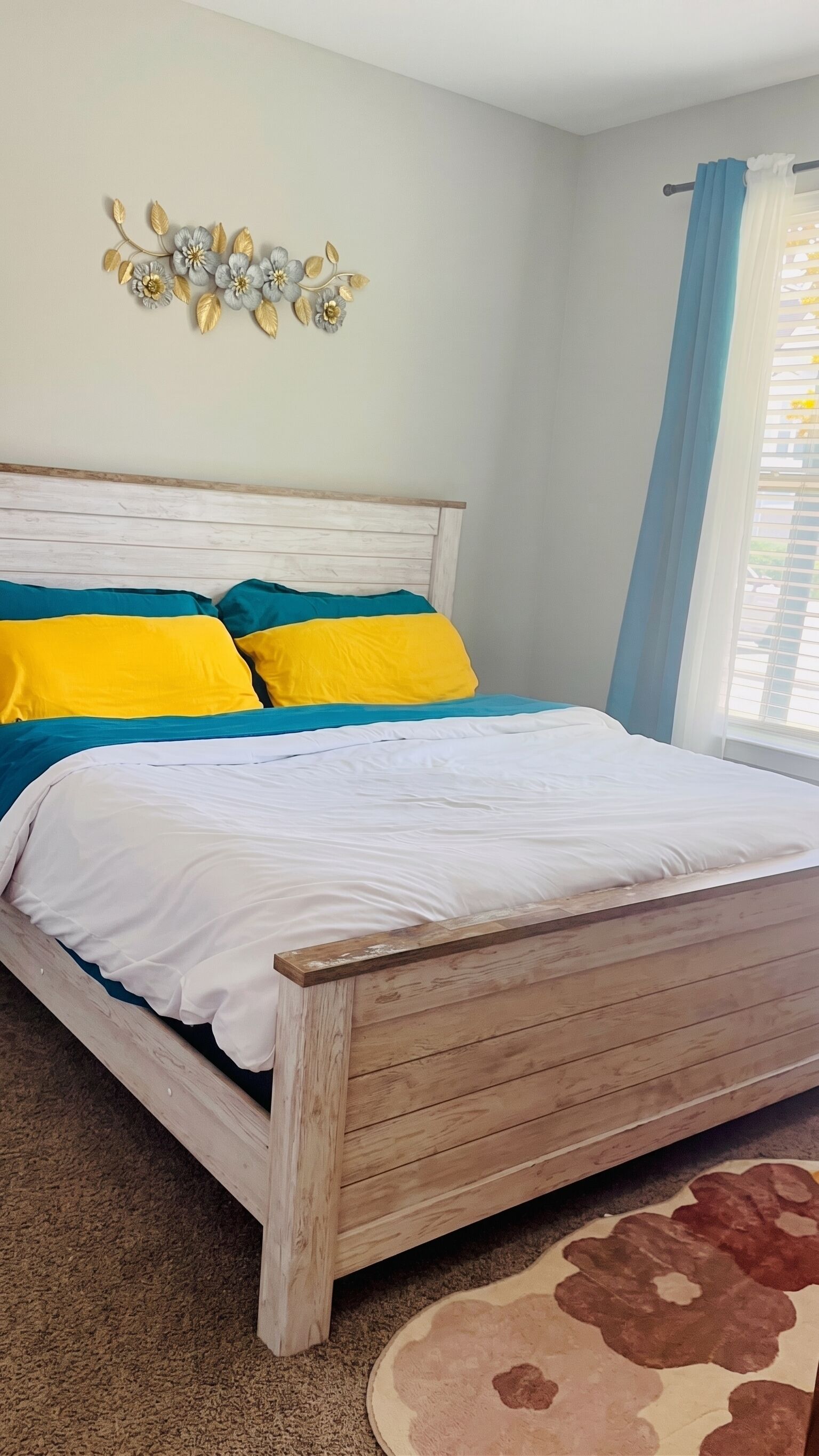 Ein Bett mit Holzrahmen, einer weißen Matratze und bunten Kissen.