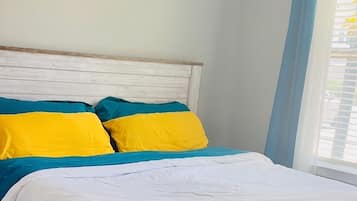Ein Bett mit Holzrahmen, einer weißen Matratze und bunten Kissen.