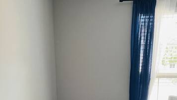 Una camera da letto con un letto, un comodino, una lampada e una finestra con tende.