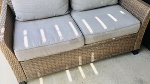 En fletsofa med grå puder på en beton terrasse.