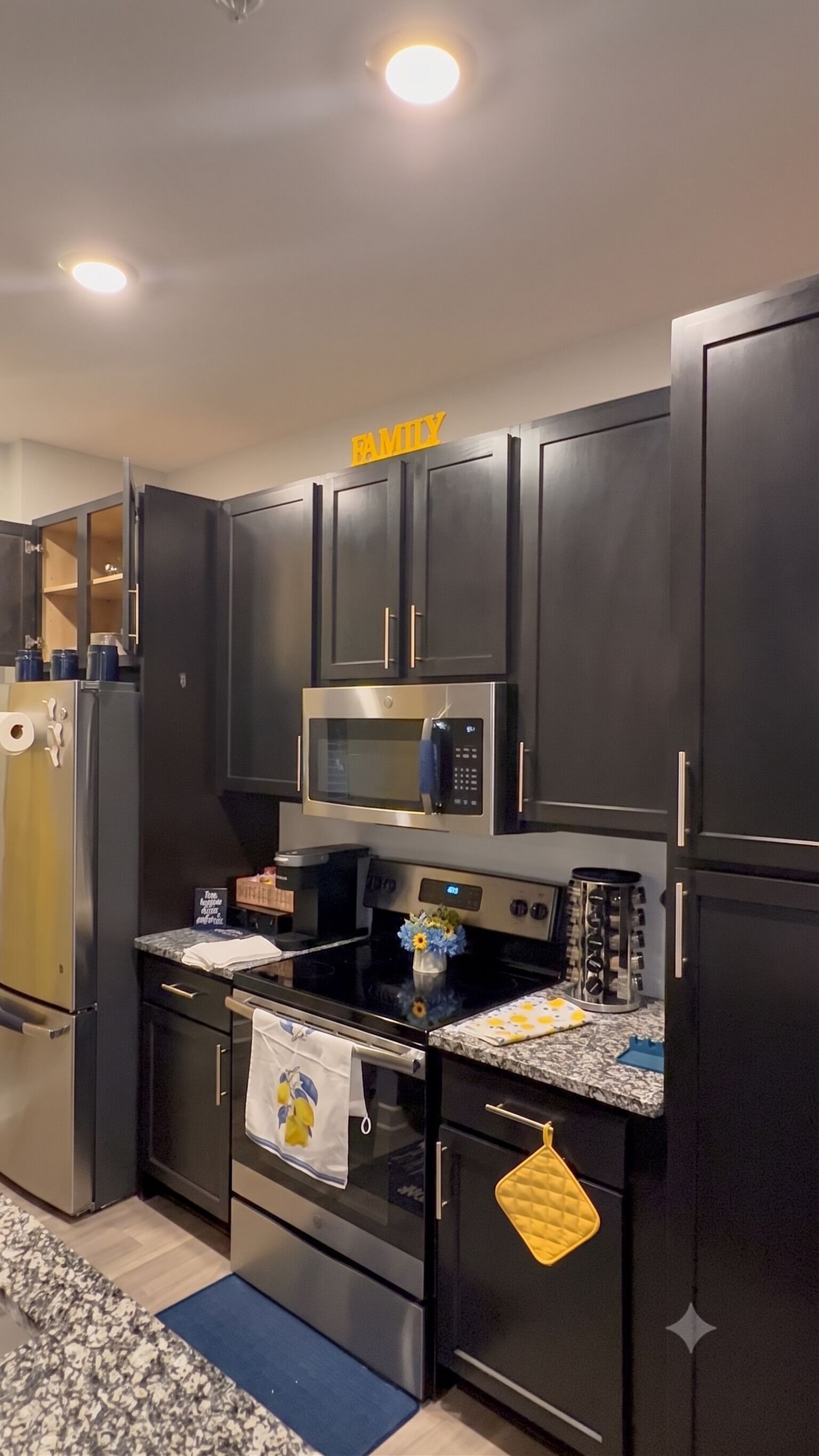Una cocina moderna con armarios oscuros, un microondas de acero inoxidable y una estufa.