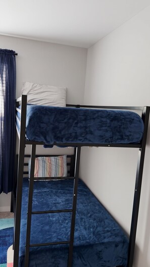 Un llit superposat amb matalàs blau i una escala.