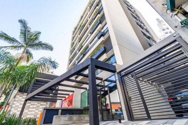 Edifici modern amb estructura metàl·lica al davant, entrada tancada per una reixa i una palmera de fons.