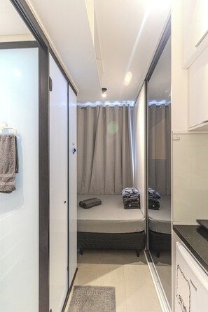 A compact room with a bed, a small table, a mirror, and a door leading to another room. - VN Higienópolis, 450 meters from the Santa Cecília Metro Station (São Paulo)
