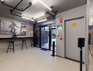 A modern interior with a reception desk, bar stools, and a visible exit door. - VN Higienópolis, 450 meters from the Santa Cecília Metro Station (São Paulo)