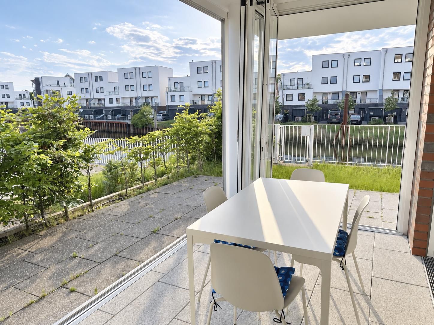 Un balcó amb taula i cadires, amb vista a una zona residencial amb edificis moderns.