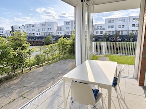 Un balcón con mesa y sillas, con vista a una zona residencial con edificios modernos.