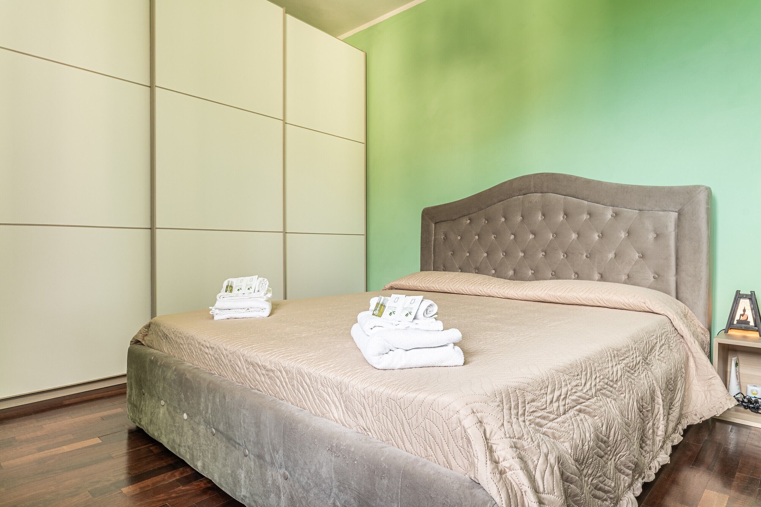 Une chambre d’hôtel avec un lit, un mur vert et un plancher en bois.