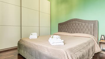 A hotel room with a bed, a green wall, and a wooden floor.
