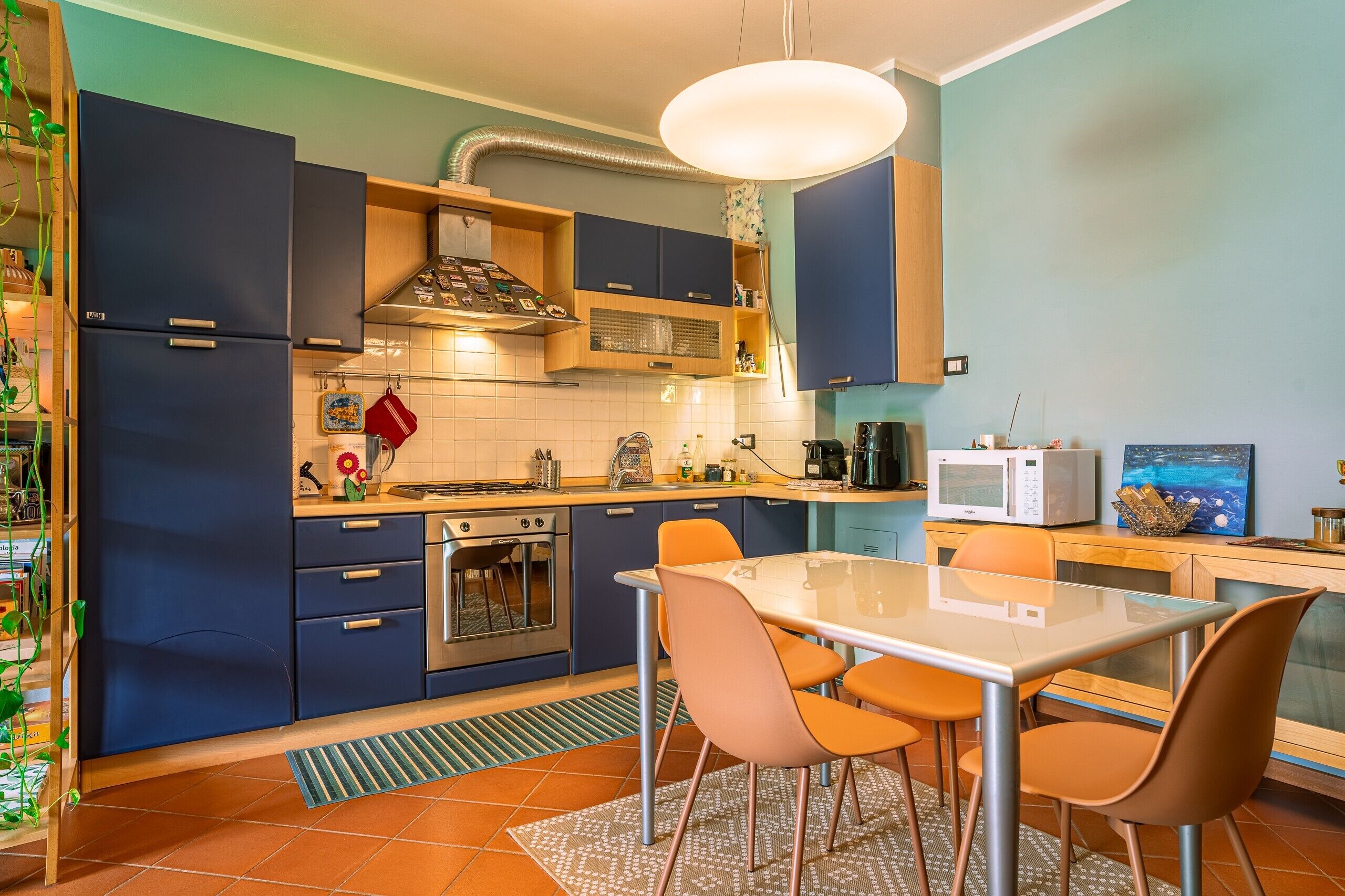 Een moderne keuken met een eethoek, voorzien van een fornuis, oven, magnetron en een tafel met stoelen.
