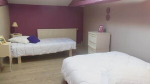 A bedroom with two beds, a nightstand, a dresser, and a lamp. - Gite proche Puy duFou (La Boissière-de-Montaigu)