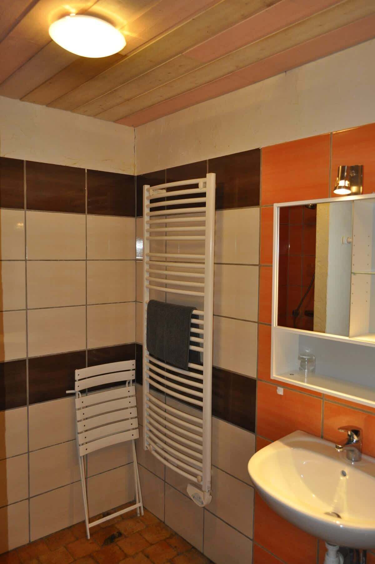 Un baño con lavamanos blanco, un espejo y un toallero.