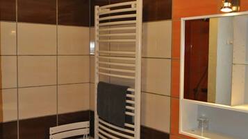Un baño con lavamanos blanco, un espejo y un toallero.