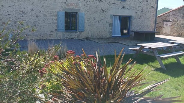 A rustic stone building with a wooden table and benches in the yard. - Gite proche Puy duFou (La Boissière-de-Montaigu)