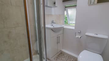 Une salle de bain avec une douche, un lavabo, des toilettes et une fenêtre.