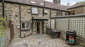 A stone building with a small entrance, a gas canister, and a paved courtyard.