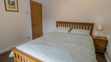 Une chambre à coucher avec un lit en bois, une table de chevet, une lampe et une porte.
