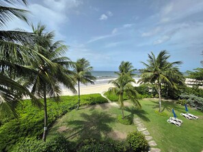 A tropical beach view with palm trees, a pathway, and beach chairs. - 304 Ocean One Condos Luxury Beachfront Vacation Rental in Barbados (Maxwell)