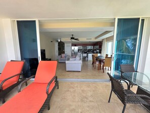 A modern living area with a sofa, chairs, a dining table, and a kitchen in the background. - 304 Ocean One Condos Luxury Beachfront Vacation Rental in Barbados (Maxwell)