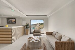 Eine moderne Hotelhalle mit einer Rezeption, einer Couch, einem Couchtisch mit Büchern, einem Fernseher und einem großen Fenster mit Blick auf Klippen.