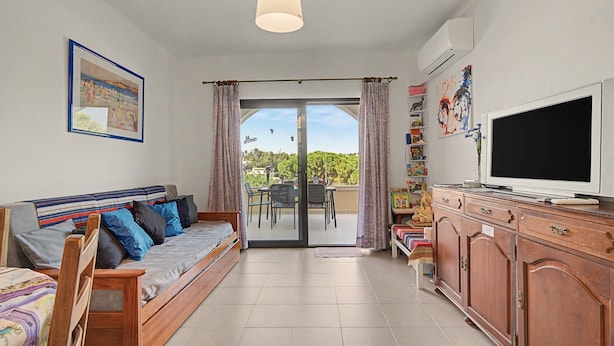 Una sala de estar con sofá, televisión y vistas al exterior.