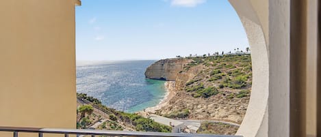 A balcony with a view of a coastal landscape, including a cliff and the sea.