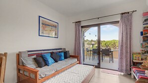 Una habitación con una cama de madera, un sofá, un área de comedor con sillas y una mesa, y vistas al exterior.