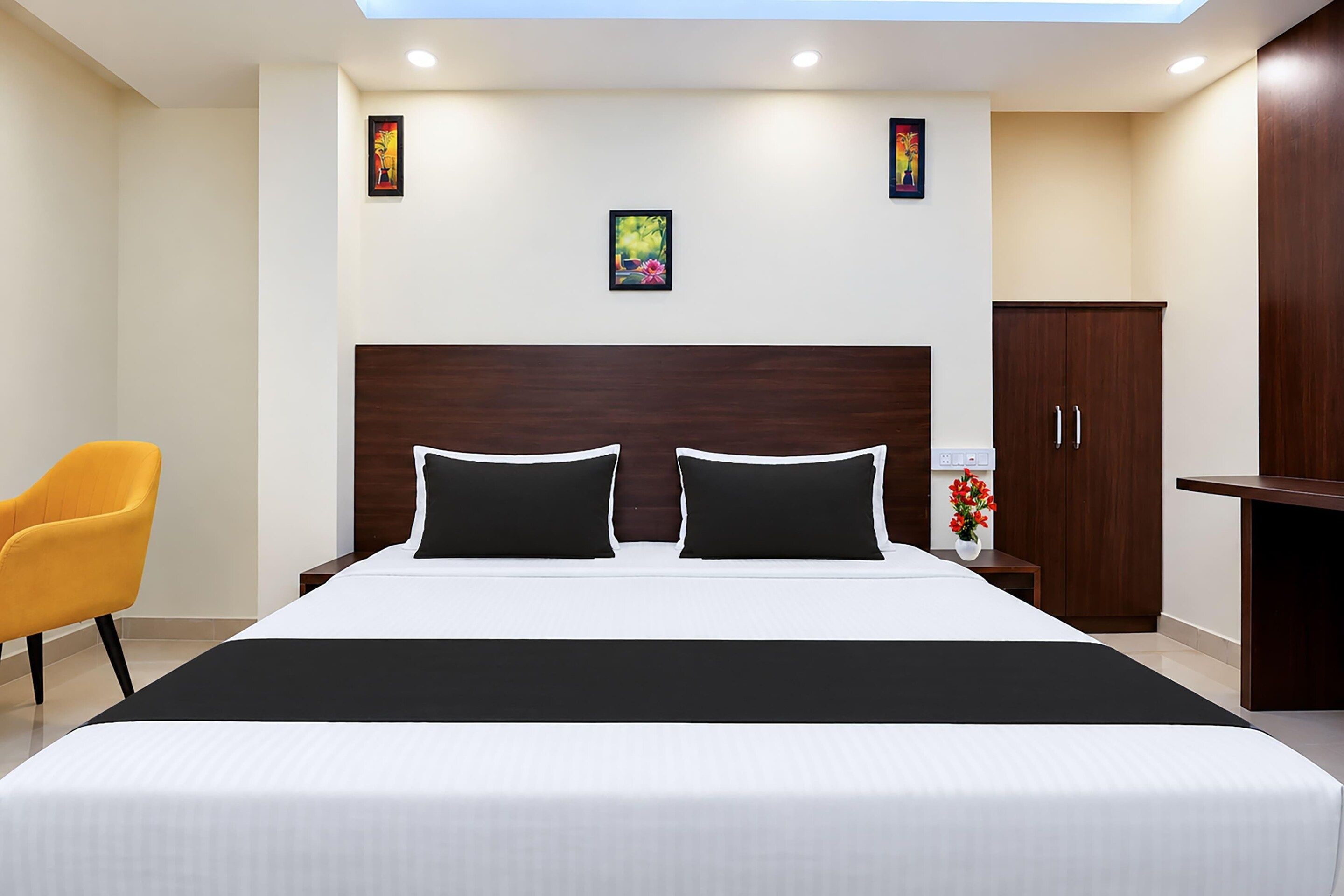 A hotel room with a large bed, a nightstand, a wardrobe, a chair, and a ceiling light.