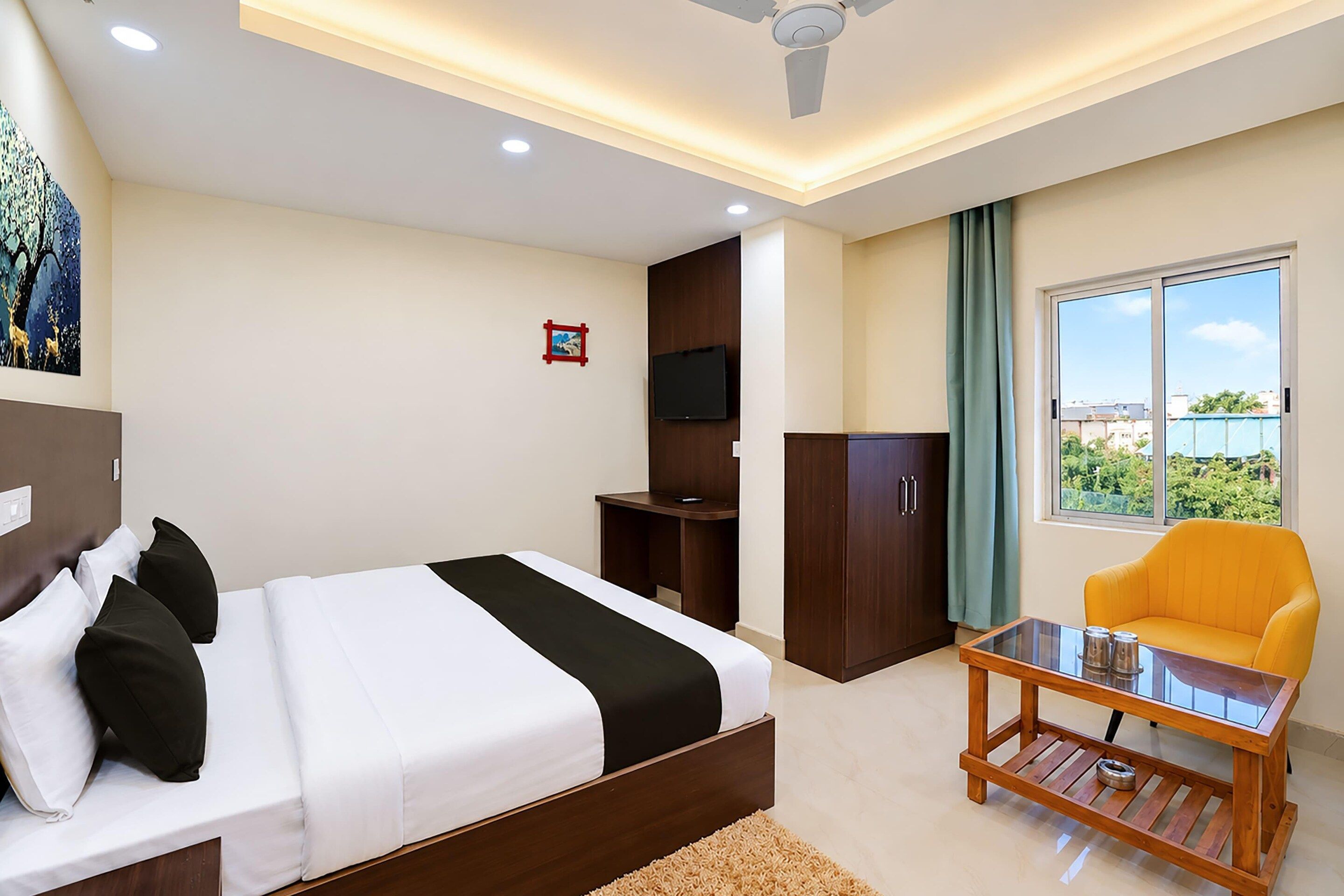 A hotel room with a bed, a television, a desk, a chair, and a window with a view.