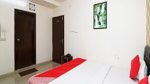 Una habitación de hotel con una cama, un ventilador de techo, un reloj y un cuadro en la pared.