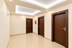 A hotel corridor with three wooden doors, each marked with a number.