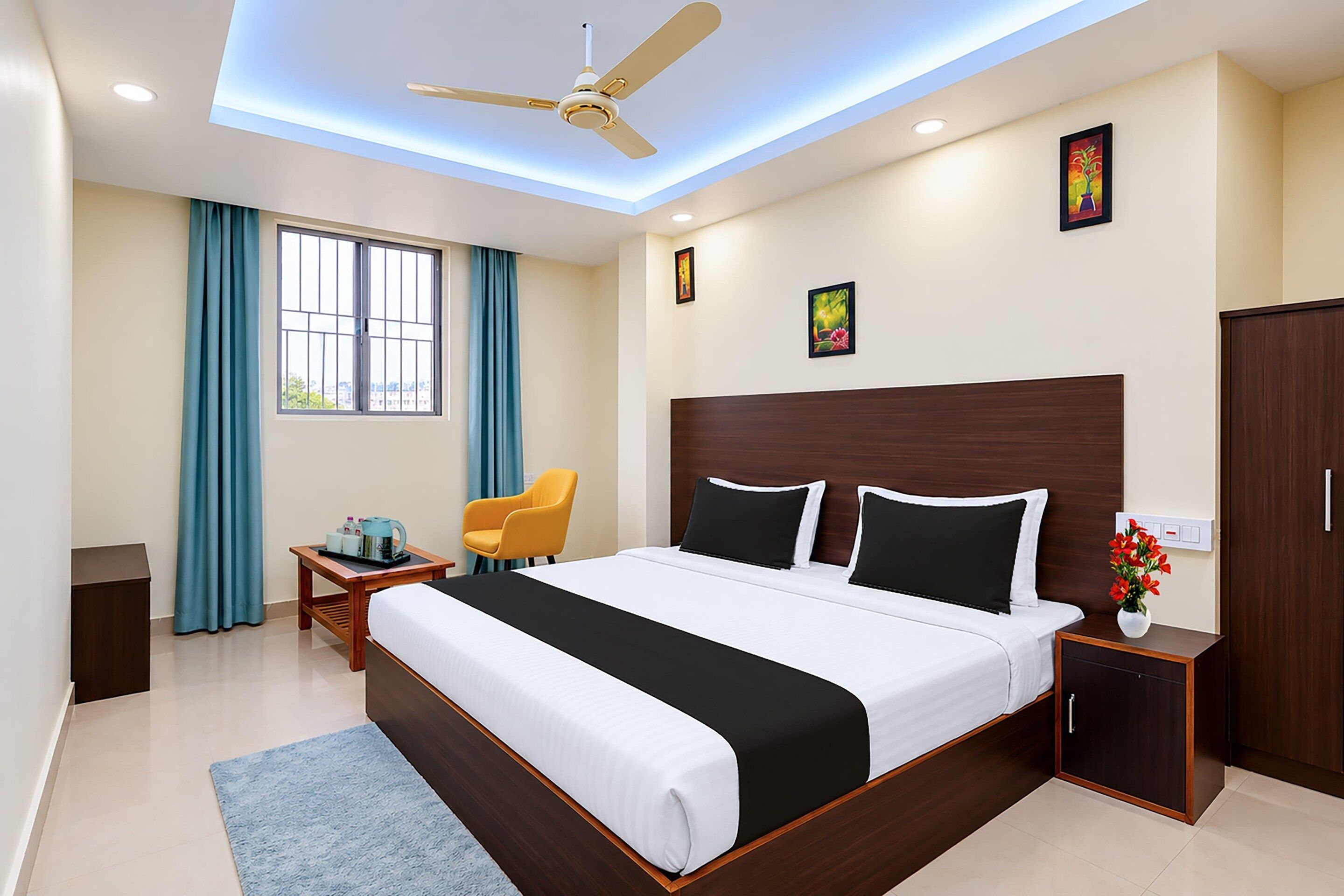 A hotel room with a bed, a desk, a chair, a wardrobe, and a ceiling fan.