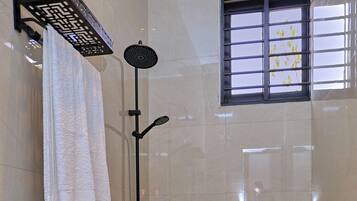 A bathroom with a toilet, a shower, and a window.