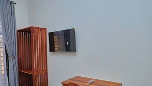 Una habitación con un armario de madera, una mesita y un televisor instalado en la pared.
