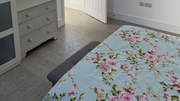 A bedroom with a bed, a wardrobe, a door leading to a balcony, and a wall-mounted light fixture. - Newly completed barn conversion in picturesque village of Sidbury. (PQ9H+949 Sidmouth)