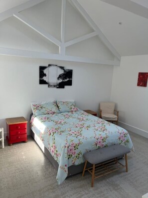 A bedroom with a bed, a chair, a nightstand, and a ceiling with exposed beams. - Newly completed barn conversion in picturesque village of Sidbury. (PQ9H+949 Sidmouth)