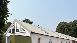 A single-story building with a gabled roof, a small porch, and a paved driveway. - Newly completed barn conversion in picturesque village of Sidbury. (PQ9H+949 Sidmouth)