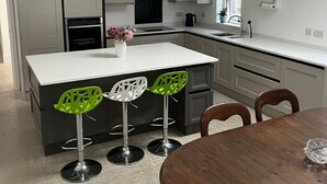 A modern kitchen with a central island, bar stools, and a dining table. - Newly completed barn conversion in picturesque village of Sidbury. (PQ9H+949 Sidmouth)