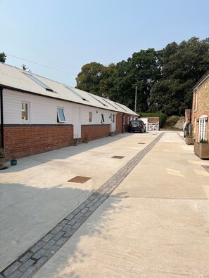 A row of single-story buildings with a paved driveway and a gated entrance. - Newly completed barn conversion in picturesque village of Sidbury. (PQ9H+949 Sidmouth)